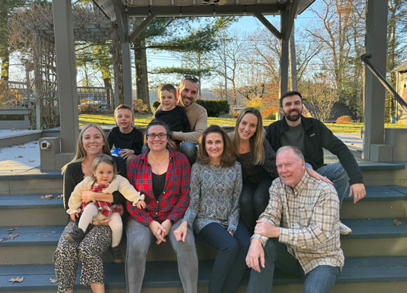 Charlotte Hillery and her family smiling for a photo while sitting on steps
