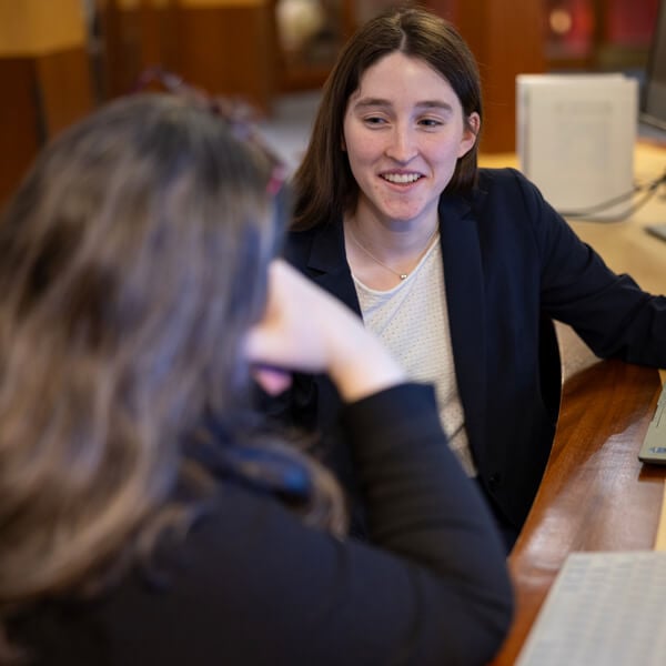 A female student smiling to a woman with her back turned to the camera