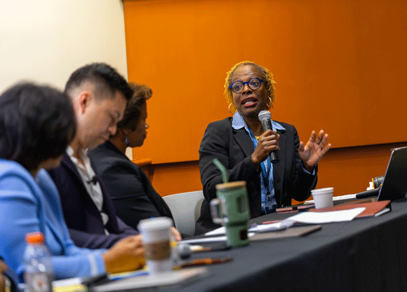 Individual holding a microphone sitting down at a panel